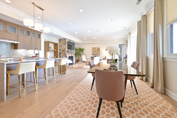 A modern, open-concept kitchen and dining area with light wood floors, neutral tones, and elegant furnishings in a well-lit room.