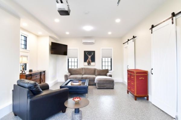 This image shows a modern living room with a sectional sofa, wall-mounted TV, armchair, coffee table, and decorative items, including a deer art piece.