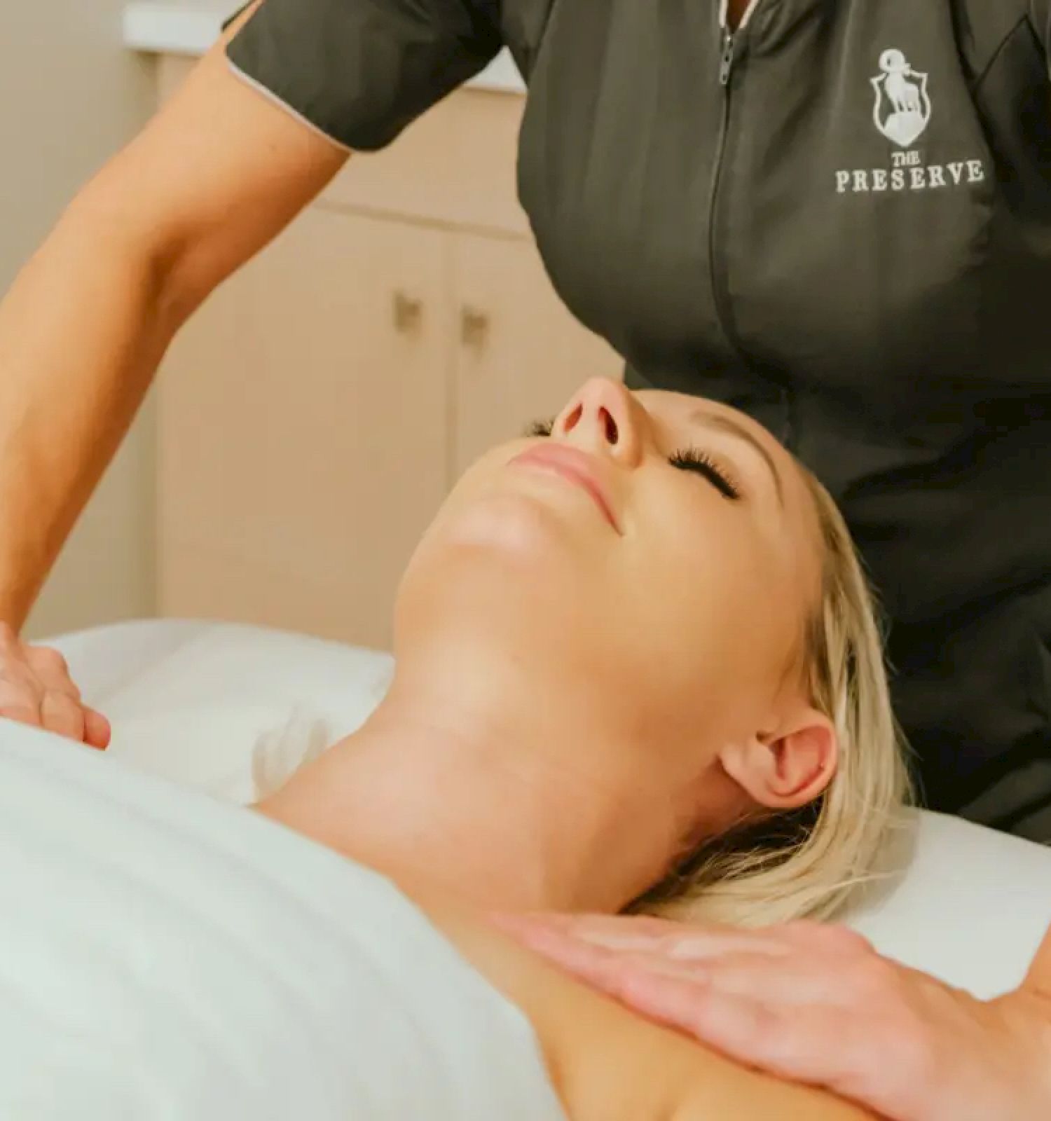 A person receiving a relaxing massage from a therapist in a professional setting, with the therapist wearing a uniform.