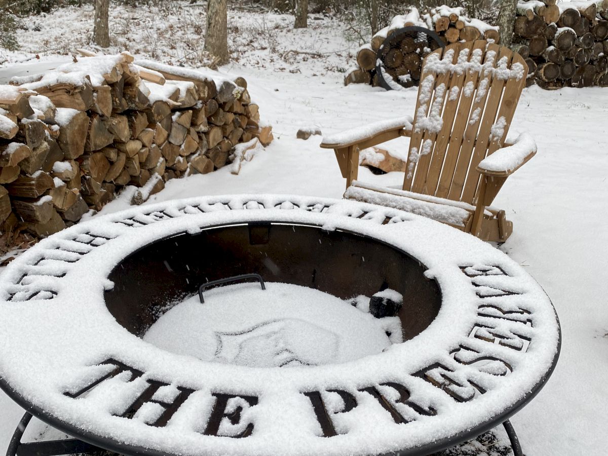 The image shows a snowy scene with a fire pit featuring the words 