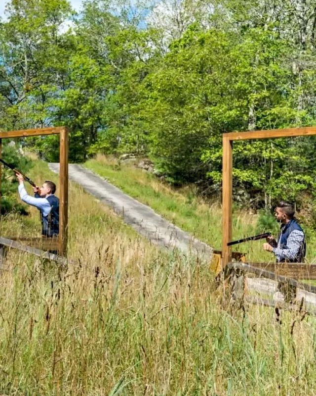 Two people are framing each other through empty picture frames outdoors, surrounded by trees and tall grass, holding rectangular devices.