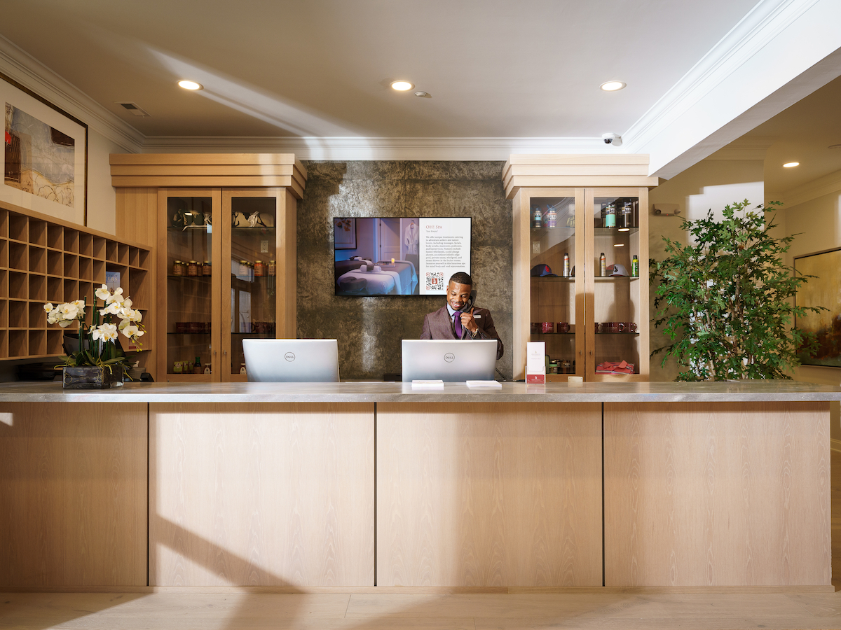 Front desk at the Hilltop Lodge, The Preserve Sporting Club & Resort, with warm lighting and elegant wooden decor.