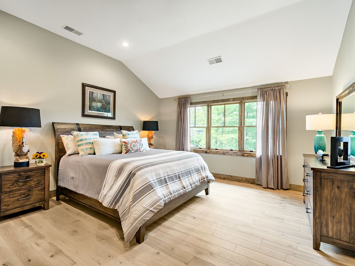 Spacious bedroom in a Single Family Home with wooden furniture, large windows, and cozy, decorative accents.