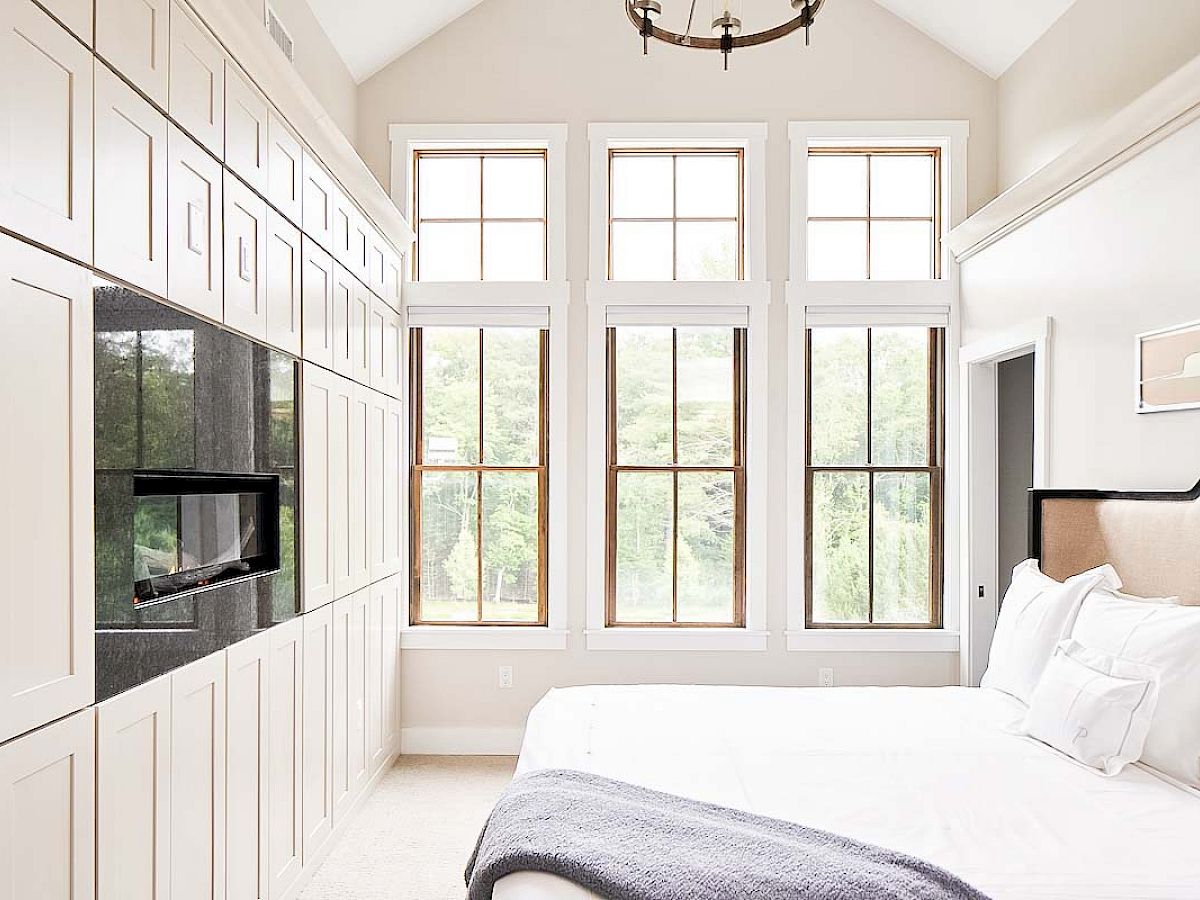 Bright and modern bedroom in a Townhome on the Green, featuring built-in cabinets, a sleek fireplace, and large windows with natural light.