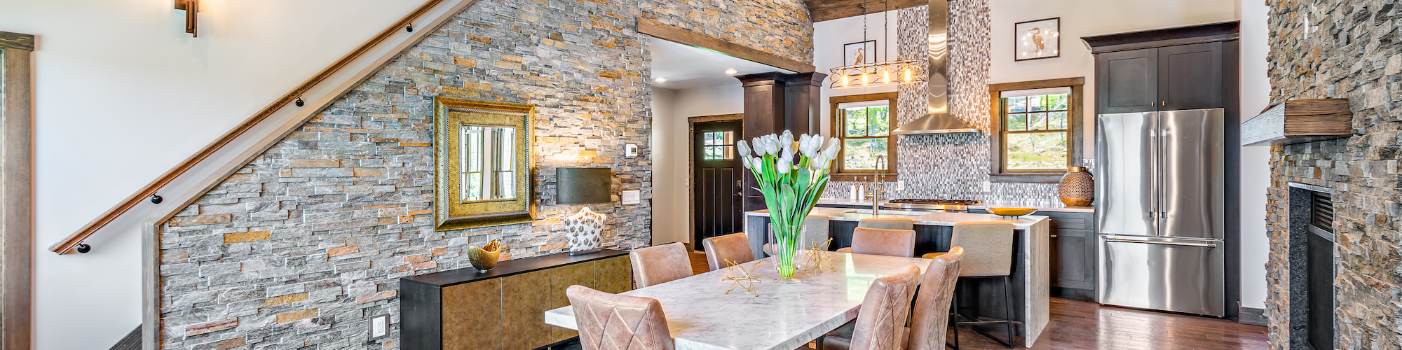 Open concept kitchen and dining space in Mayfly Unit 1 at Preserve Resort & Spa and Event Venue, featuring a large island, modern appliances, and elegant seating area under a unique antler chandelier.