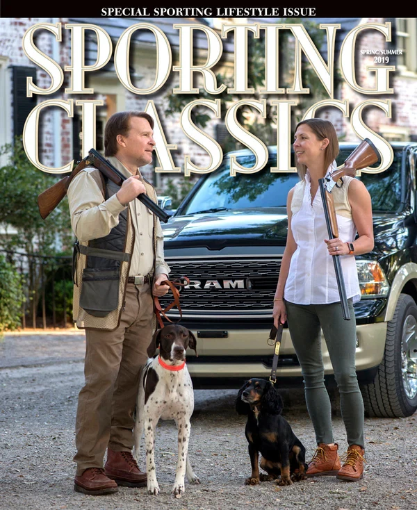 Two people with guns and dogs stand outside in front of a large vehicle, featured on the cover of "Sporting Classics" magazine, special issue.