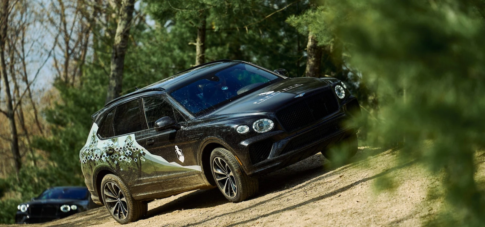 Bentley Bentayga driving uphill on a dirt trail at The Preserve Sporting Club