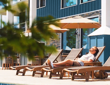 A guest enjoys a sunny day by the pool at The Preserve Resort & Spa.