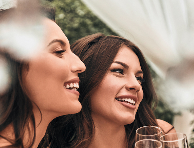 Two women smiling and holding glasses of champagne, likely at a celebration or special event.